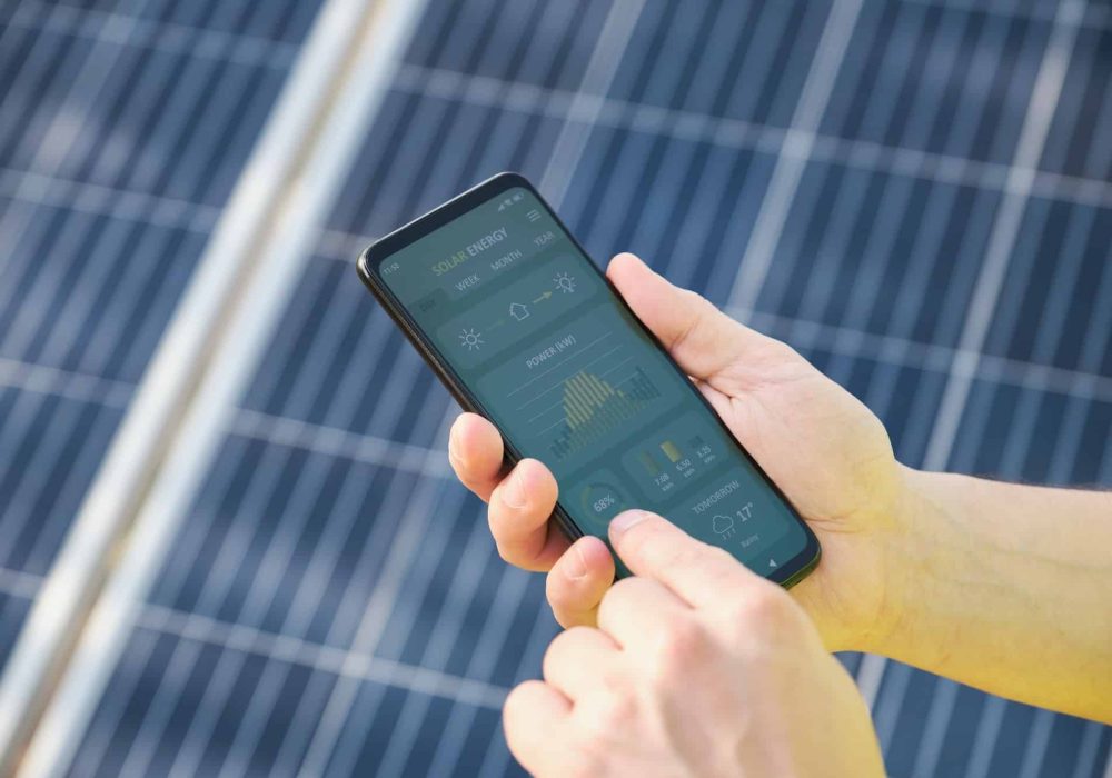 Hands checking solar power generation in a smartphone app.