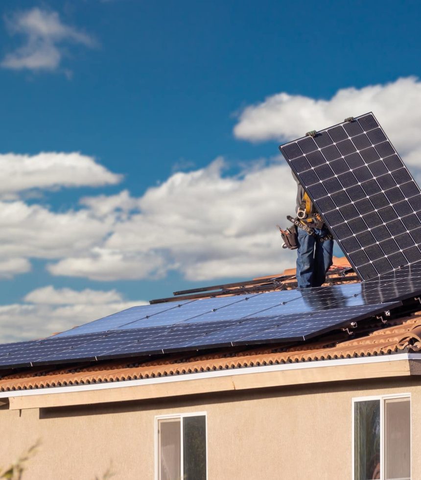 Workers Installing Solar Panels on House Roof